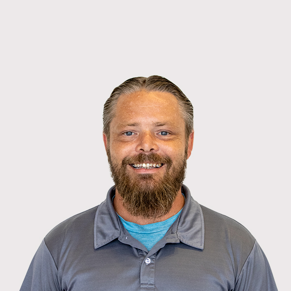 Smiling man with a full beard and short hair, wearing a gray polo shirt.